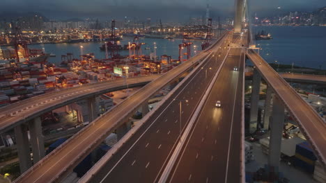 Tráfico-En-El-Puente-Del-Picapedrero-Chino-Sobre-El-Puerto-De-Contenedores-Iluminado-En-Hong-Kong