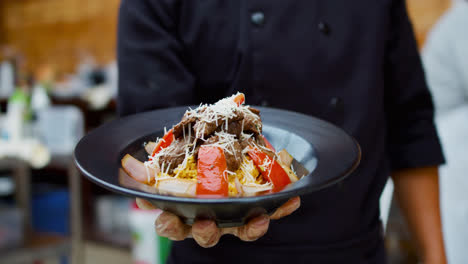 Amazing-slow-motion-and-zoom-in-shot-of-the-presentation-of-a-Peruvian-dish-called-Lomo-Saltado-while-a-cook-holds-it-in-one-hand