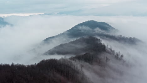 Misty-mountain-peaks-emerging-above-soft-clouds,-serene-and-majestic