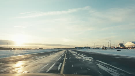 Airport-inspection-vehicle-riding-on-snowy-taxiway-full-of-ice-in-winter-sunset