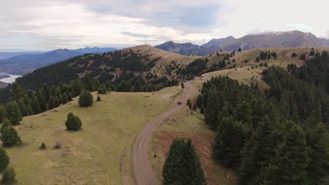 Coches-A-Lo-Largo-De-Sinuosos-Caminos-De-Tierra-Seca-A-Lo-Largo-De-La-Cresta-Del-Bosque-Con-Grandiosas-Montañas-De-Agrafa-Grecia