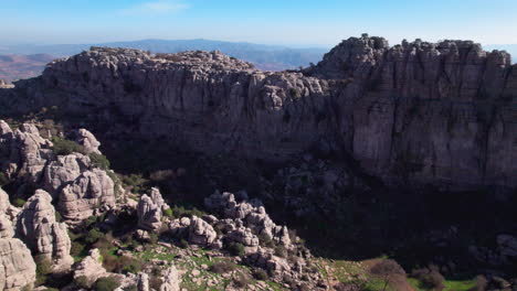 Aerial-forward-dolly-shot-of-nature-reserve-at-El-Torcal-de-Antequera,-Malaga,-Andalusia,-Spain,-revealling-the-nearby-village-and-landscape-on-a-clear-day