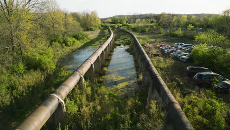 A-junkyard-in-fayetteville,-ar,-with-cars-and-lush-greenery,-on-a-sunny-day,-aerial-view