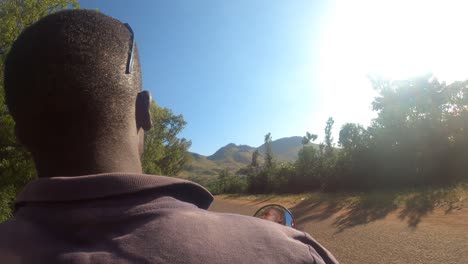 Toma-De-Punto-De-Vista-De-Un-Hombre-Africano-Conduciendo-Un-Taxi-En-Moto-A-Través-De-Un-Remoto-Paisaje-Rural-De-Montaña-Africano