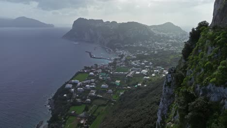 Coastal-view-of-Capri,-Italy-with-lush-greenery-and-a-serpentine-road,-cloudy-sky,-overlooking-the-Tyrrhenian-Sea
