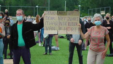Elderly-couple-holding-a-protest-sign-during-peaceful-rally-in-the-Netherlands,-protest-for-black-lives-matter-movement