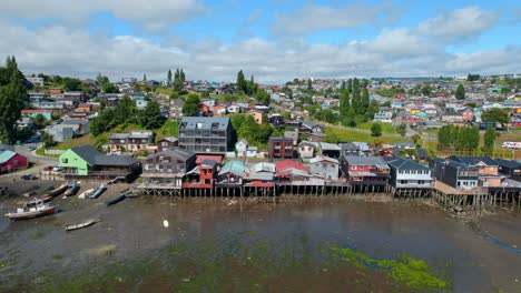 Colorful-stilt-houses-at-Castro-houses-and-boats,-cloudy-skies,-aerial-view