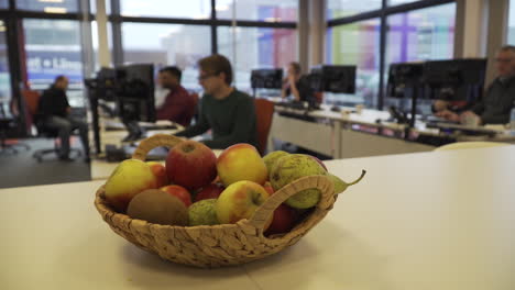Close-up-of-healthy-fruit-basket-in-an-office-with-people-working-in-background