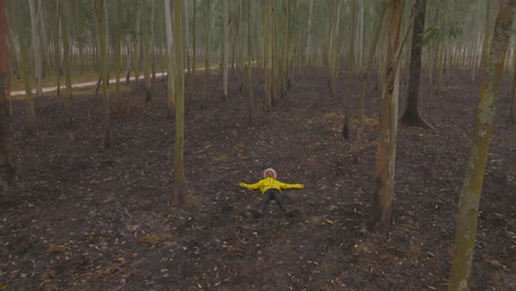 Drone-shot-reveals-a-male-in-yellow-jacket-lying-on-forest-ground-and-relaxing-in-Terai-region-of-Eastern-Nepal