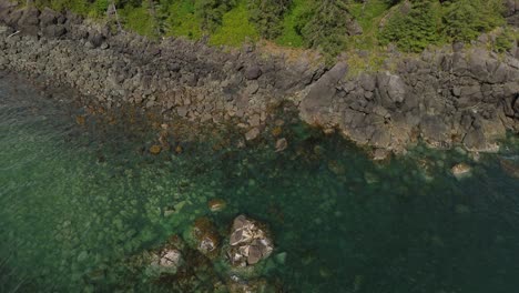 Pedestal-Drone-Shot-Over-Rocky-Coastal-Area-near-Sandpit,-Grey-Bay,-Canada
