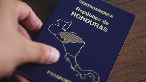 A-man's-hand-places-the-Honduran-passport-on-a-wooden-table-during-routine-airport-screening