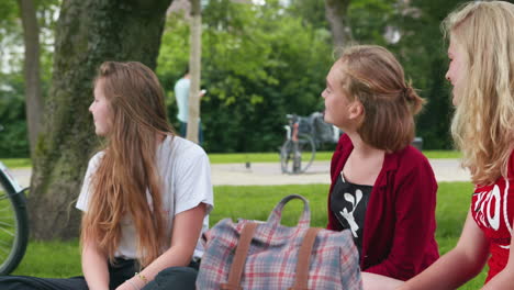 Tres-Chicas-Jóvenes-Afuera-Mirando-Por-Encima-De-Sus-Hombros-En-Un-Parque-Verde,-Cámara-Lenta