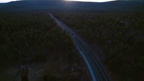 Drohnenaufnahme-Des-Verkehrs-Auf-Der-Autobahn-In-Der-Landschaft-Von-Arizona,-USA-Bei-Sonnenuntergang,-Kiefernwald-Und-Autos-Auf-Der-Straße