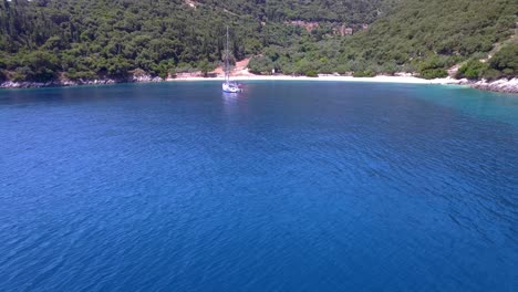 Foki-beach-in-kefalonia-with-turquoise-waters-and-a-single-yacht,-aerial-view