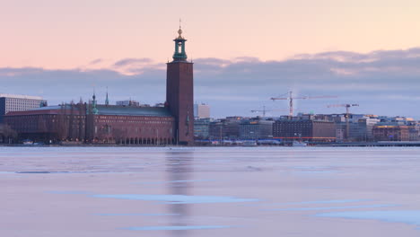 Aerial-over-iced-Riddarfjärden-with-Stockholm-City-Hall-view-in-twilight-sky