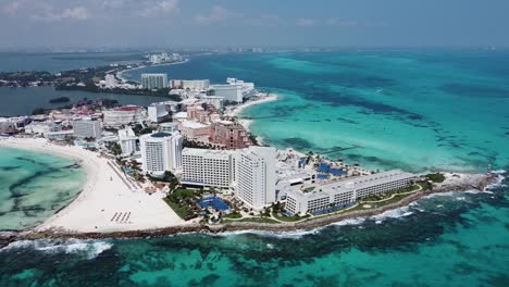 Cancun-coastline-with-resorts,-clear-blue-ocean,-and-white-beaches,-sunny-day,-aerial-view
