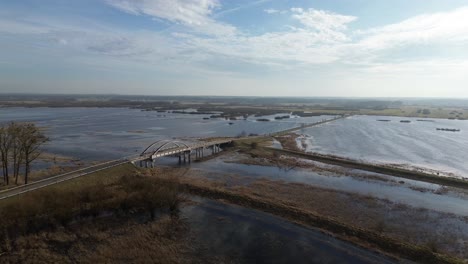 Tiro-Largo-Aéreo-área-Inundada-Agua-Río-Desbordamiento-Puente-Carretera-Soleado