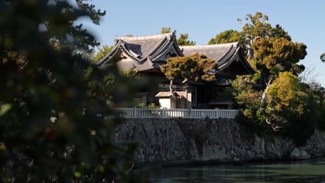 Beautiful-Japanese-ancient-shrine-surrounded-by-trees-on-calm-day