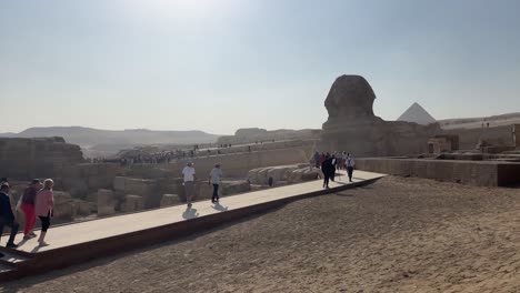 Los-Turistas-Caminan-Por-La-Esfinge-Y-Las-Pirámides-En-Egipto,-Bajo-Un-Cielo-Despejado.