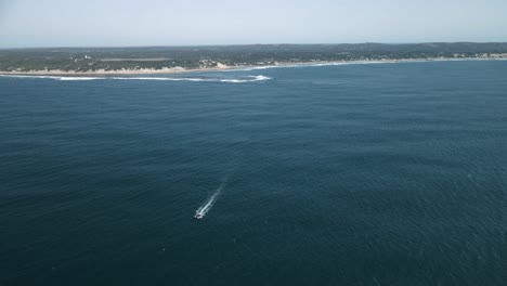 high-aerial-shot-of-a-boat-heading-out-to-sea-from-the-coast-of-mozambique