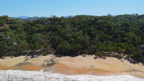 Drone-rising-over-secluded-beach-in-Sayulita,-Mexico