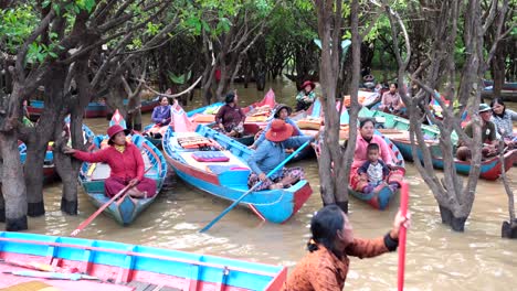 The-villagers-are-seated-in-their-modest-traditional-boats,-eagerly-anticipating-tourists-to-join-them-for-a-serene-voyage-through-the-lake-forest-of-Kampong-PhlukVillage