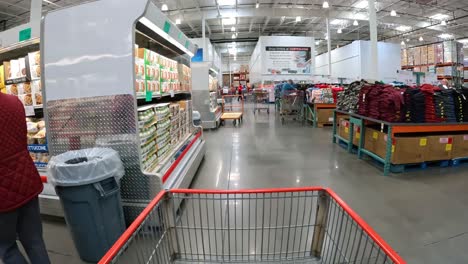 POV---Langsames-Schieben-Eines-Einkaufswagens-Zwischen-Den-Kühlvitrinen-Und-Tischen-Mit-Kleidungsauslagen-Im-örtlichen-Costco