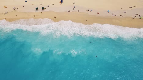 Myrtos-Strand-Mit-Türkisfarbenem-Wasser-Und-Sonnenanbetern-Auf-Dem-Goldenen-Sand,-Kefalonia,-Luftaufnahme