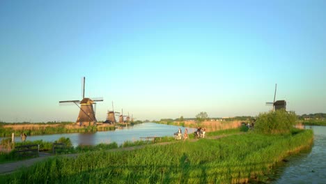 Touristen-Radeln-Durch-Kinderdijk,-Traditionelle-Holländische-Windmühlenlandschaft