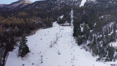 Close-up-descending-aerial-shot-of-skiers-and-snowboarders-racing-down-the-slopes-at-Bear-Mountain-ski-resort-in-Big-Bear-Lake,-CA