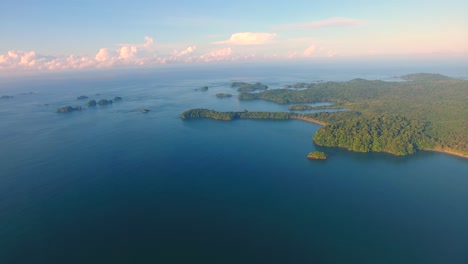 Panning-aerial-view-high-above-the-green-jungle-covered-Parida-Island-at-golden-hour-in-paradise