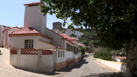 Small-old-houses-renovated-and-painted-white-and-yellow-on-the-hillside,-with-Castelo-de-Vide-in-the-background