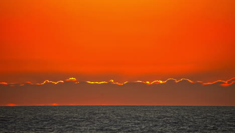 Red-Sunrise-Timelapse-Over-Sea-From-Behind-Cloud-with-Telephoto-Close-Up