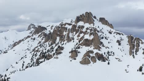 Majestic-snowy-Ciucas-Mountains-peaks-under-cloudy-skies,-aerial-view