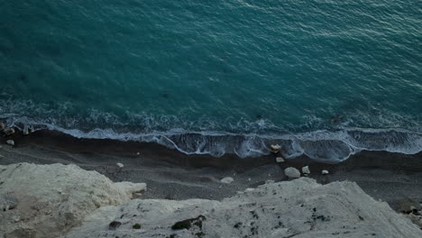 Ruhige-Wellen-Rollen-In-Der-Dämmerung-über-Den-Steilen,-Felsigen-Strand-Der-Aphrodite-In-Kouklia,-Zypern-–-Luftaufnahme-Von-Oben