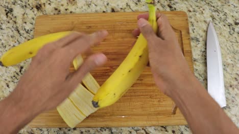 Peeling-bananas-with-hands,-POV-shot-from-top