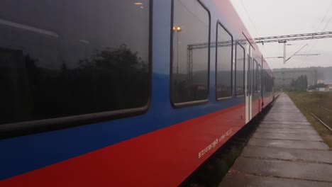 Belgrade---Bar-railway-and-The-Srbija-Voz-wagons-leaving-the-train-station-on-a-foggy-rainy-autumn-day,-Uzice,-Serbia