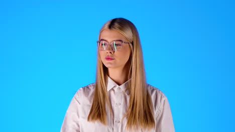 Caucasian-Young-Blonde-Woman-with-Reading-Glasses-Eats-a-Red-Apple,-Studio-Shot