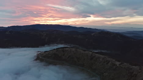 Neblige-Bergstraßen-Bei-Sonnenaufgang-Mit-Weichen-Wolken-Und-Sanftem-Licht,-Luftaufnahme