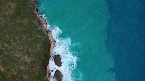 Drone-top-down-pan-across-Caribbean-island-coastline-with-sand-in-undertow-and-deep-blue-drop-off,-bird's-eye-view