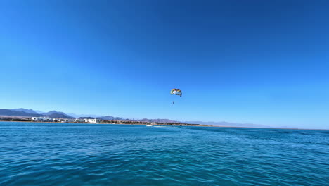 Person-parasailing-near-tropical-coastline,-motion-view