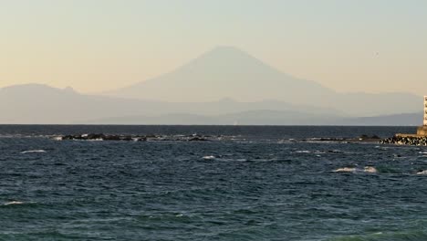 Slow-cinematic-tilt-up-over-ocean-with-Mount-Fuji-silhouette-in-distance