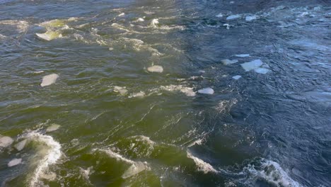 Chilly-stream-with-floating-ice-floes,-sunlight-reflecting-on-water