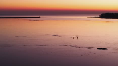 Tranquil-sunset-at-Port-Colborne-with-reflections-on-calm-water,-silhouette-of-pier-visible