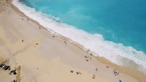 Playa-De-Myrtos-Con-Aguas-Turquesas-Y-Bañistas-Dispersos-En-La-Arena,-Cefalonia,-Grecia,-Vista-Aérea