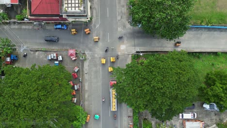Aerial-top-down-view-of-cargo-truck-and-tricycles-driving-on-rural-provincial-streets-and-intersection-in-quaint-Philippine-town