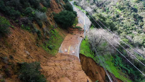 Drone-flying-over-a-earthslip,-blocked-highland-road-in-California,-United-States