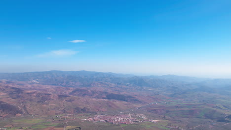 Landscape-surrounding-the-Torcal-de-Antequera-on-a-clear-day,-aerial-backward-dolly-to-reveal-the-rocky-formation