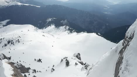 The-snow-covered-ciucas-mountains-under-a-cloudy-sky,-aerial-view