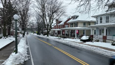 Driving-car-on-main-street-in-american-neighborhood-during-winter-snow